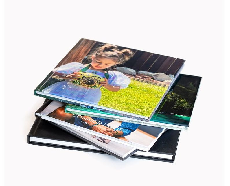 Stack of glossy photo books with colorful family photos on the covers