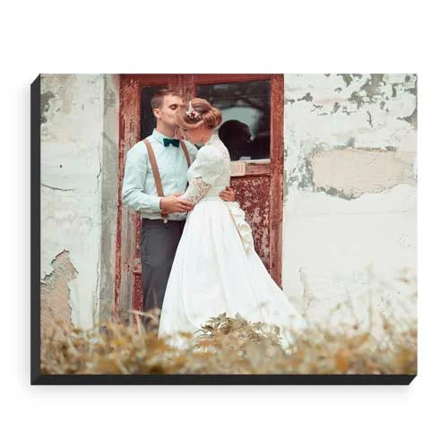 Couple embracing in front of a weathered doorway, the woman in a white dress and the man in suspenders.