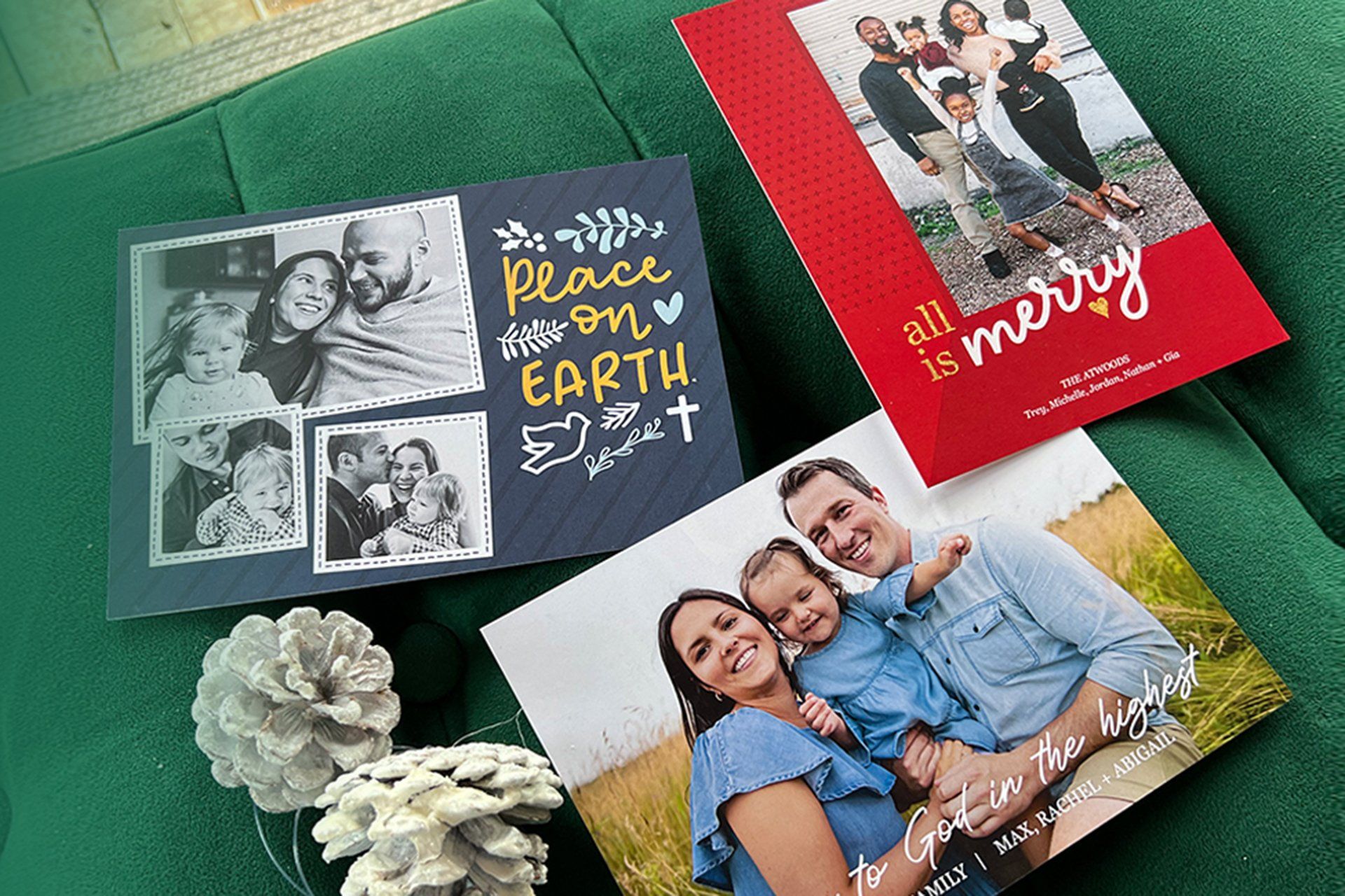 Greeting cards on a green surface, including a black “peace on earth” card and red family photo cards