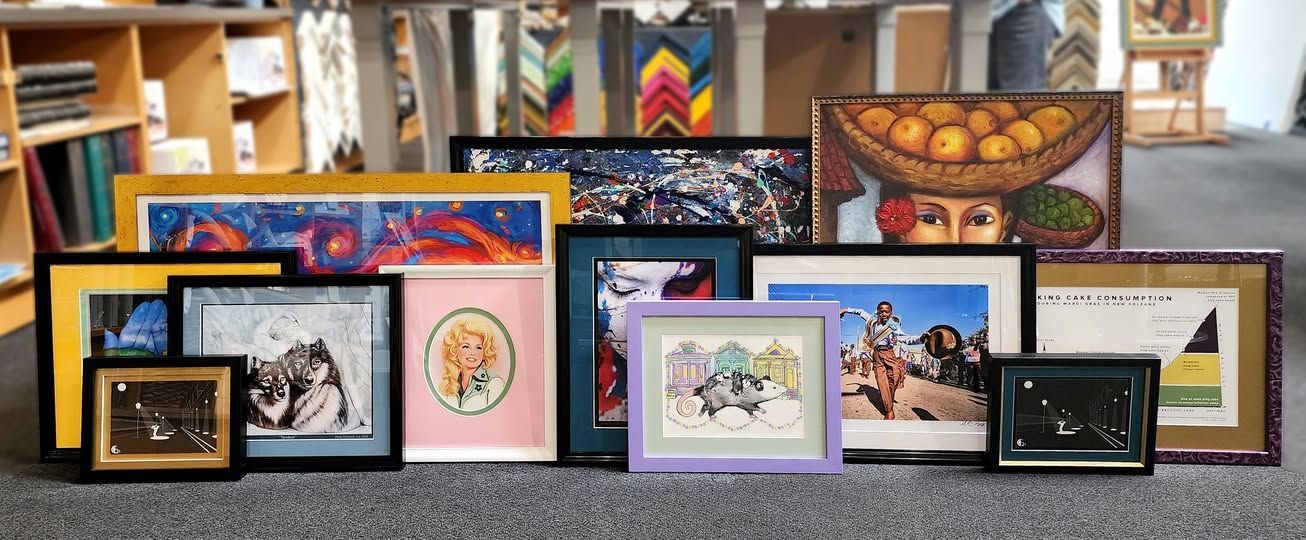 Assorted framed artwork and photos arranged on a shelf, featuring colorful decorative prints and portraits