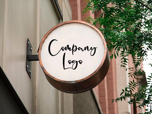 Round hanging storefront sign with “Company Logo” on a beige building exterior