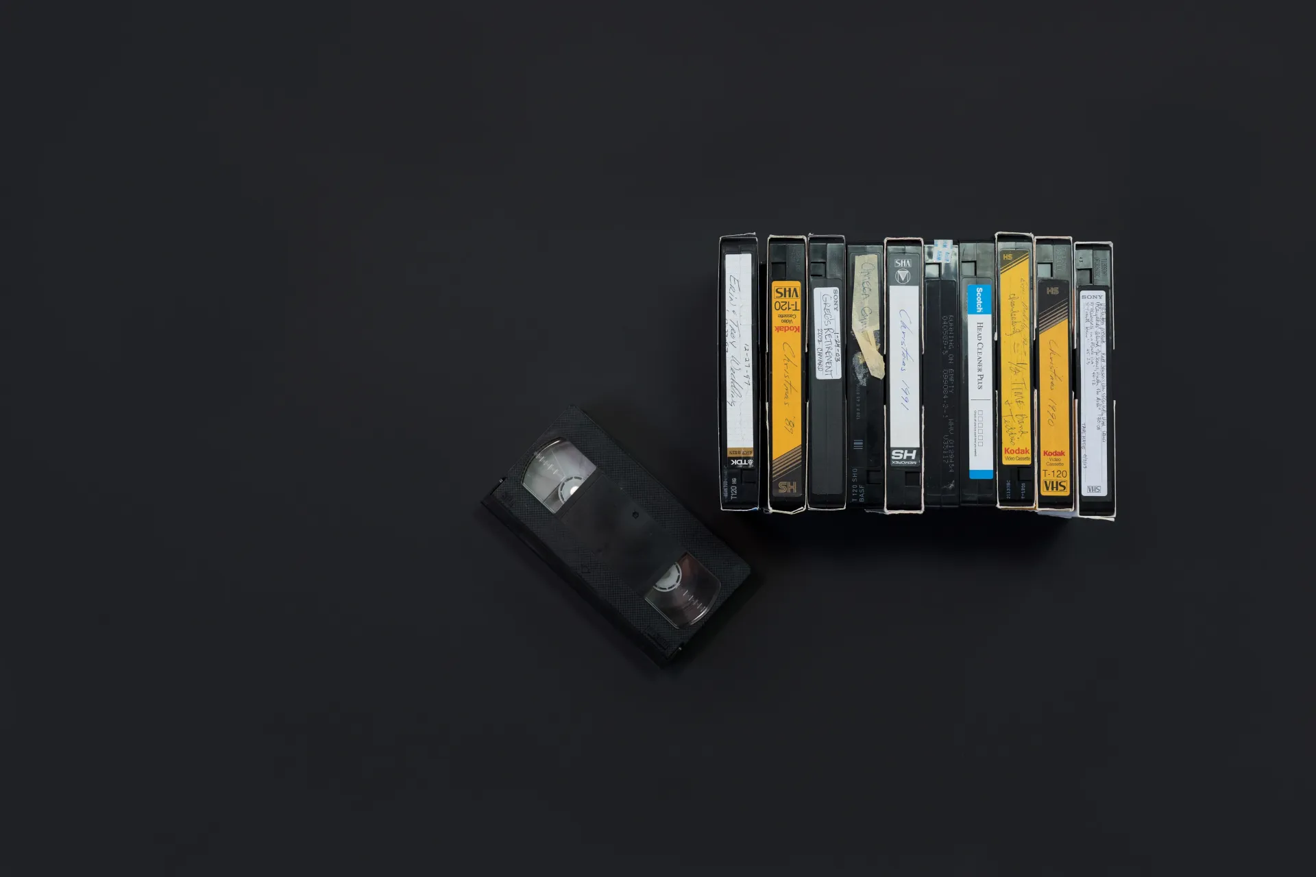 Scattered cassette tapes on a dark background, with one loose tape in front