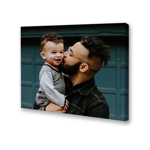 Man kissing a smiling child on the cheek in front of a blue garage door