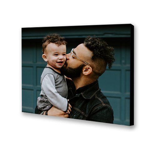 Two people smiling and hugging indoors, with a man kissing a child's cheek.