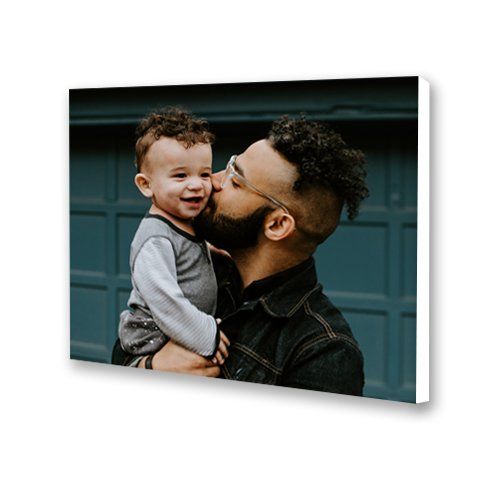 Man kissing a smiling child on the cheek in front of a teal garage door