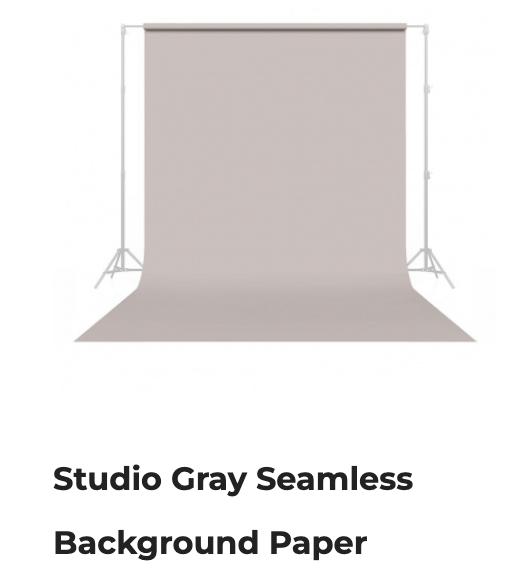 Gray seamless paper backdrop on a support stand with studio lighting fixtures.