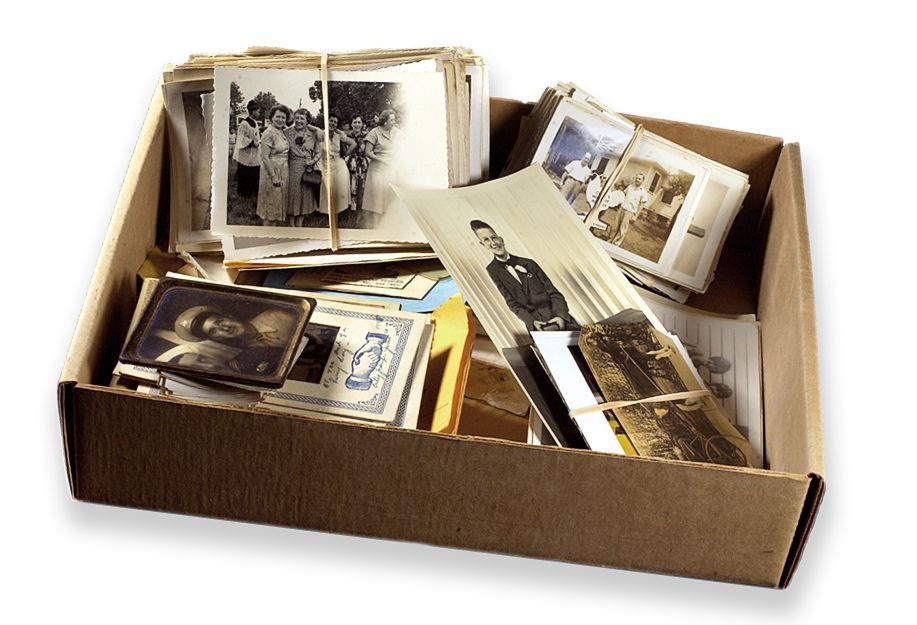 Open cardboard box filled with stacks of old black-and-white photographs