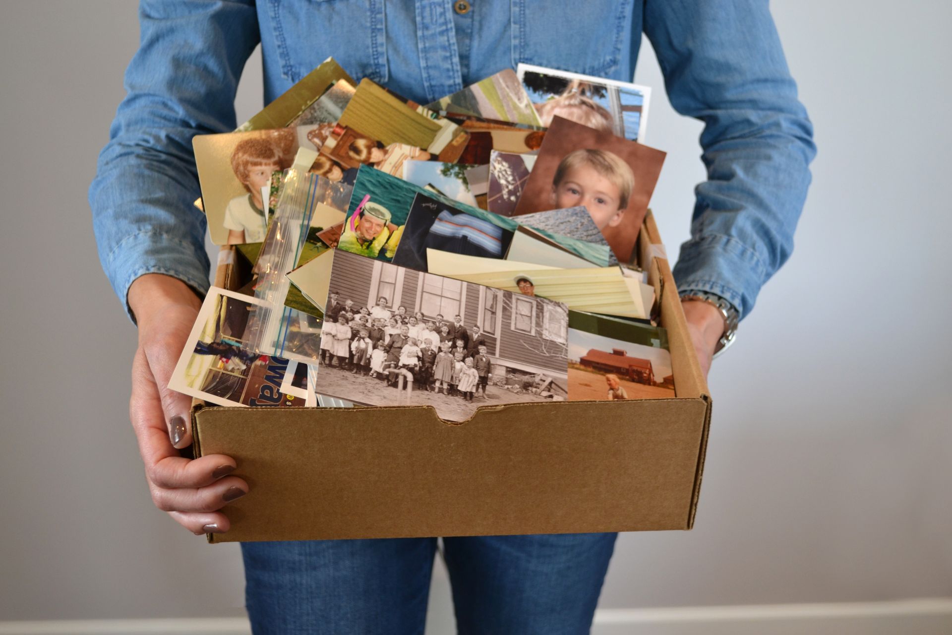 Person holding a box filled with old photographs and postcards