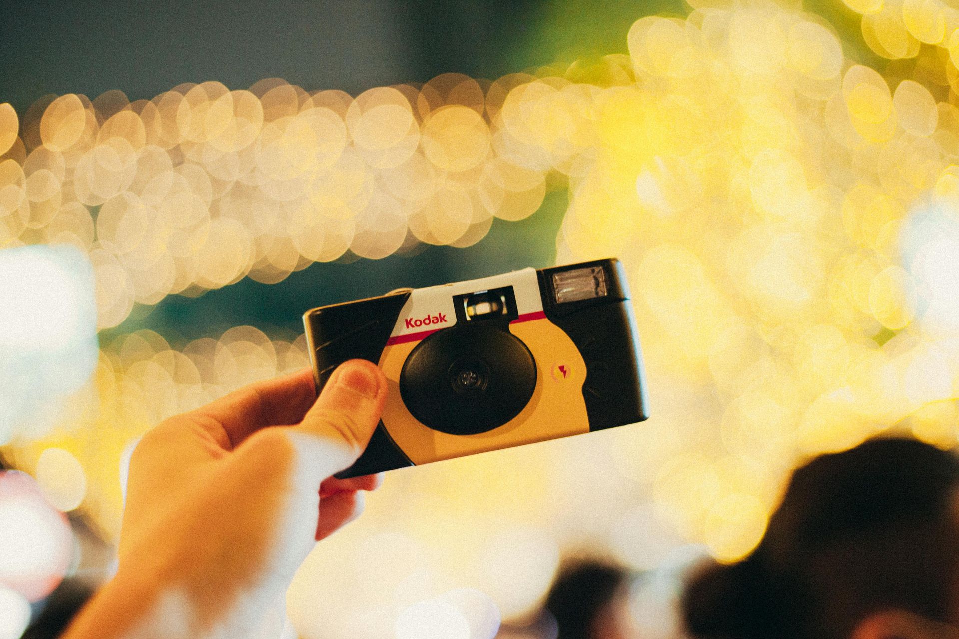 Hand holding a small camera with city lights blurred in the background