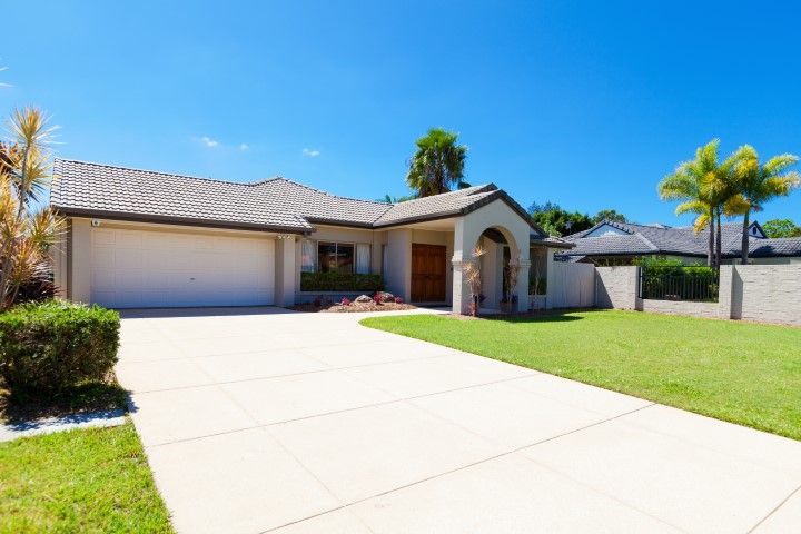 Suburban house with concrete driveway and lawn on a sunny day.