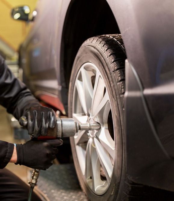A Man is Kneeling Down and Pumping Air Into a Tire — Jim Wall Automotive in Bowral, NSW