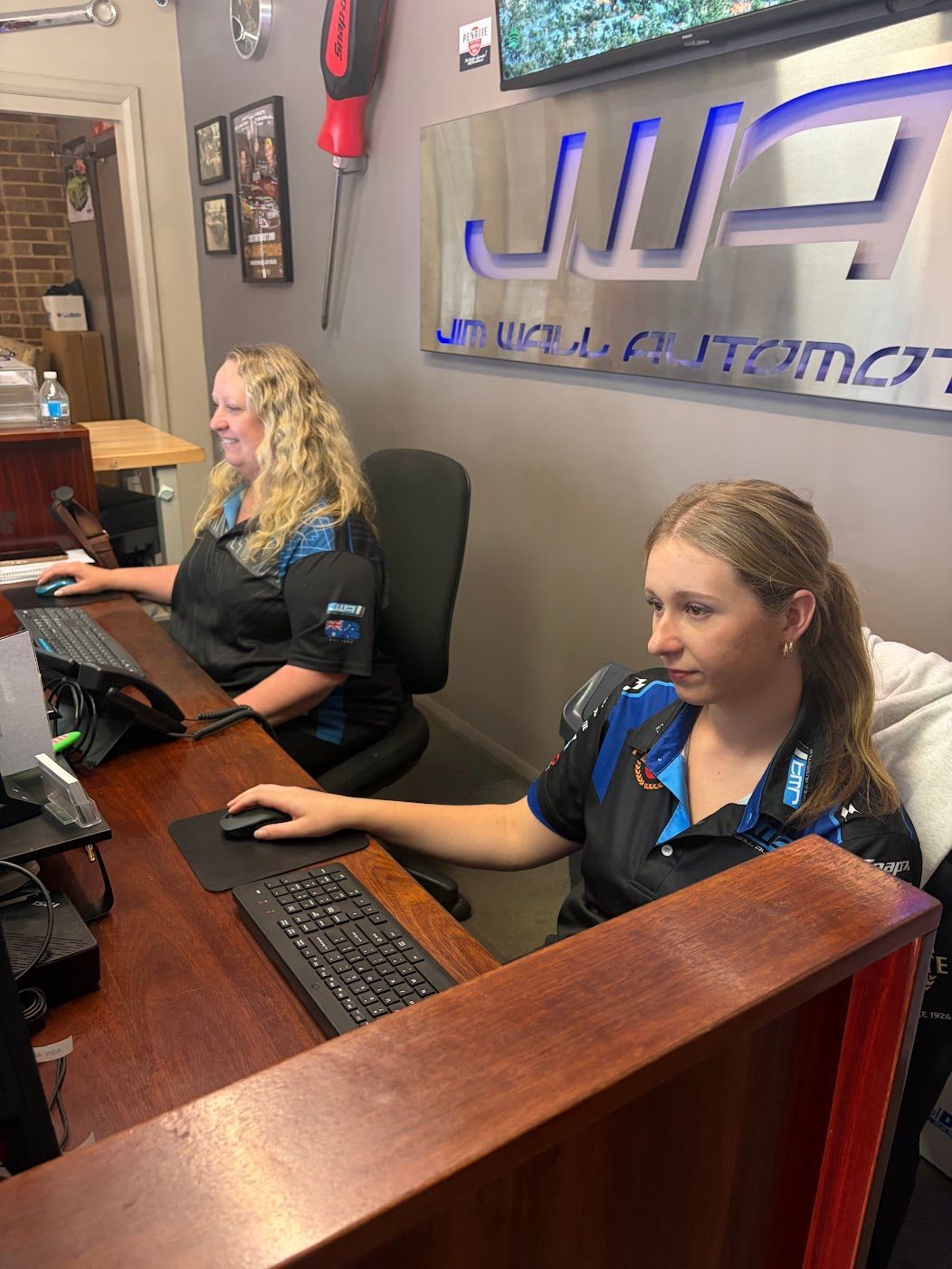 A Man and a Woman Are Sitting at a Desk in Front of a Computer β Jim Wall Automotive in Mittagong, NSW
