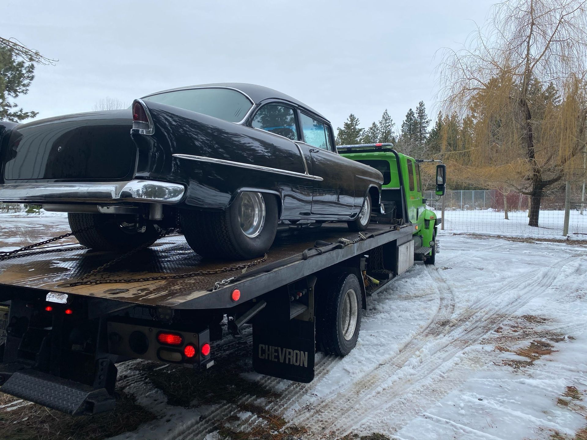 A black car is sitting on top of a tow truck.