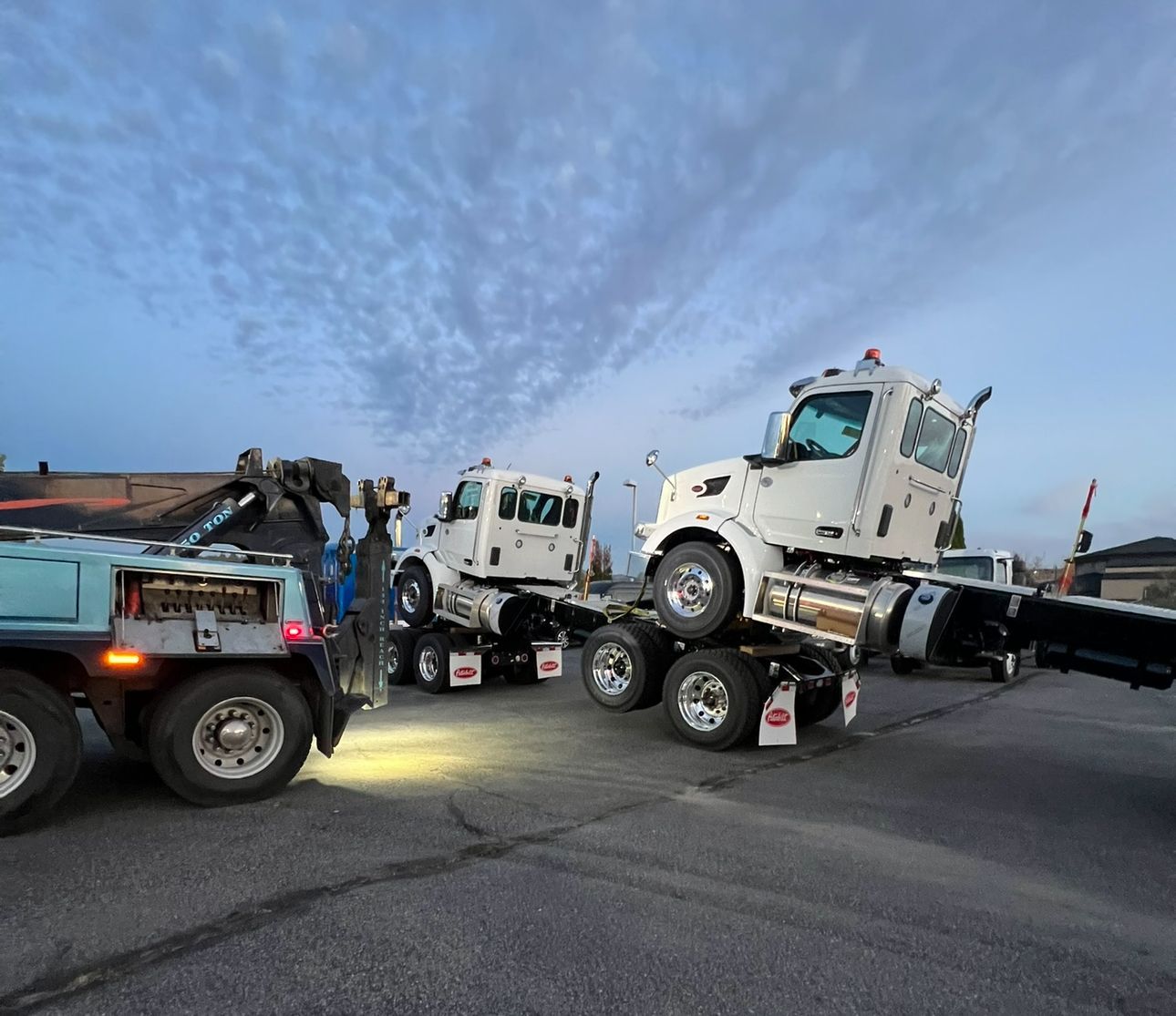 A white truck is being towed by a tow truck