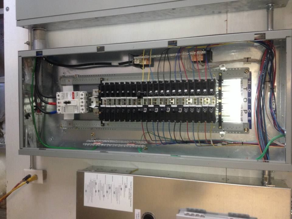 Open electrical control panel with rows of circuit breakers and wiring inside a metal cabinet