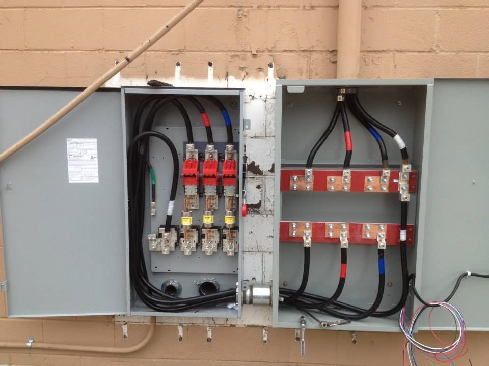 Open electrical control panel with wiring and circuit breakers mounted on a wall.