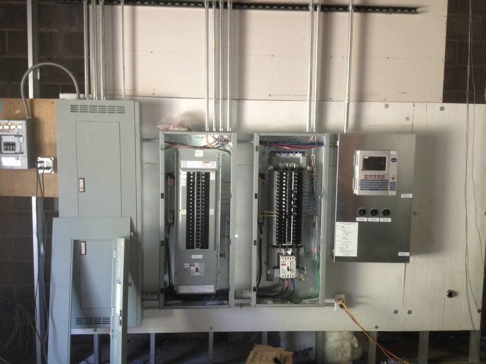 Electrical control panel room with open metal cabinets and wiring inside an industrial setting