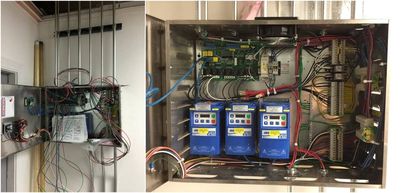 Open electrical panel with wiring, circuit breakers, and blue battery units mounted on a wall
