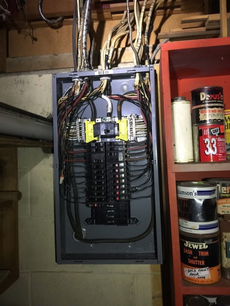 Open electrical breaker panel with many wires in a basement or utility room