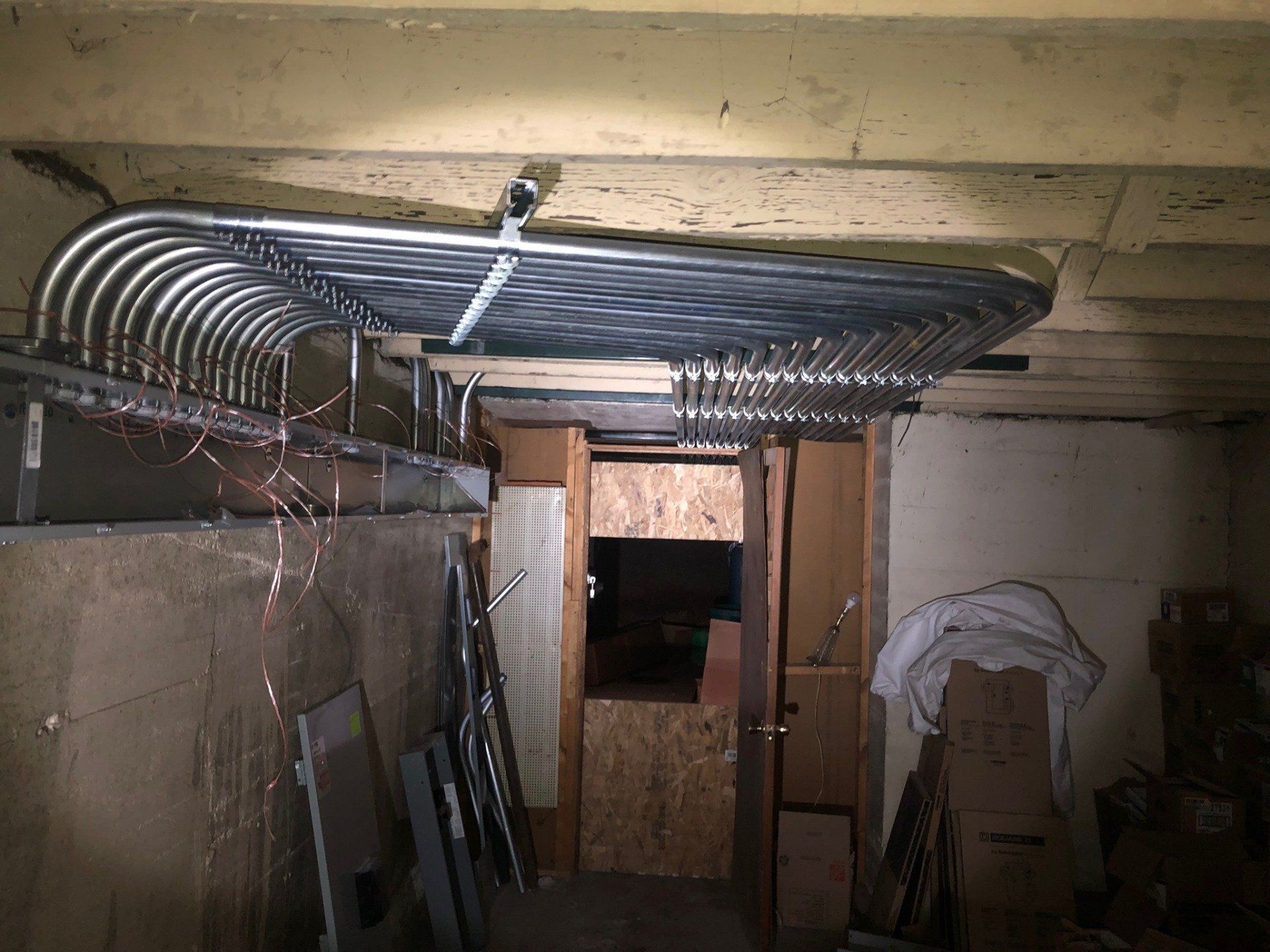Basement with exposed ductwork, wooden partitions, and stacked boards against concrete walls.