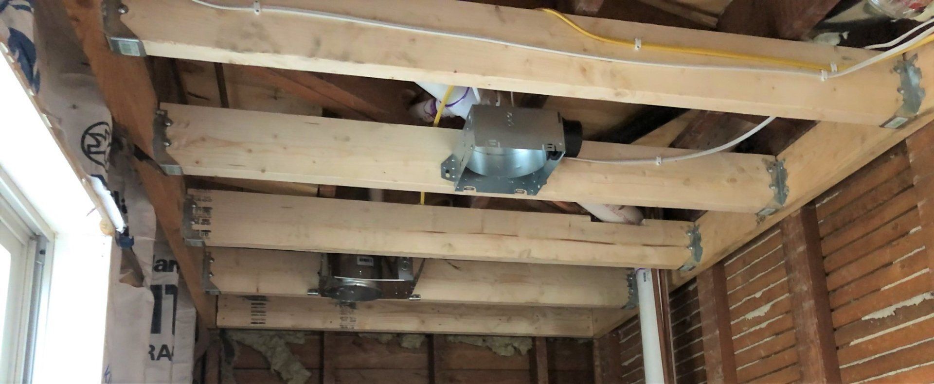 Interior of a wooden structure with exposed ceiling beams, wiring, and utility boxes under renovation
