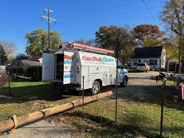 White service van in a driveway beside a house, with a trailer and fenced yard on a sunny day.