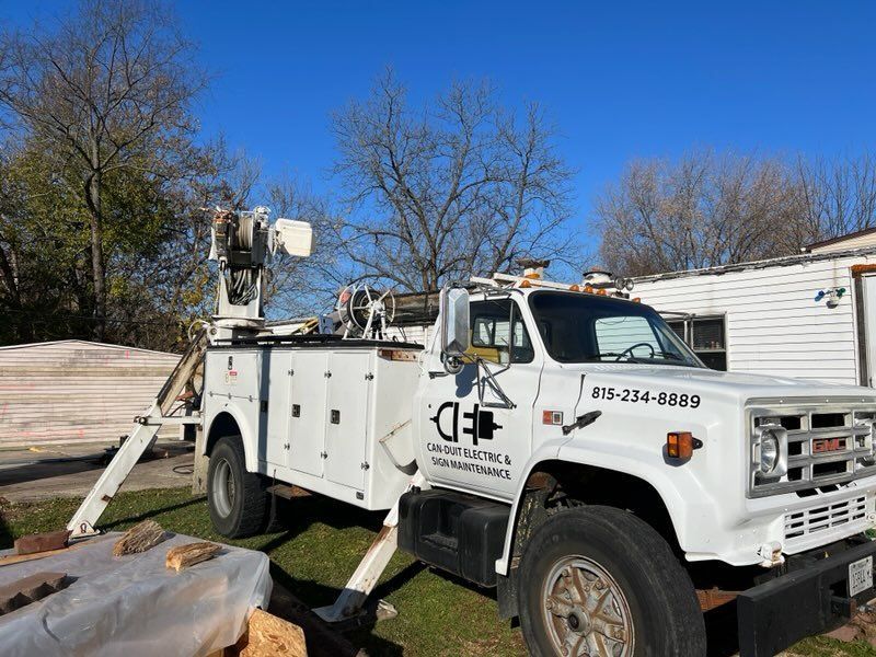 White utility truck with lift equipment parked on grass beside a house under a clear blue sky