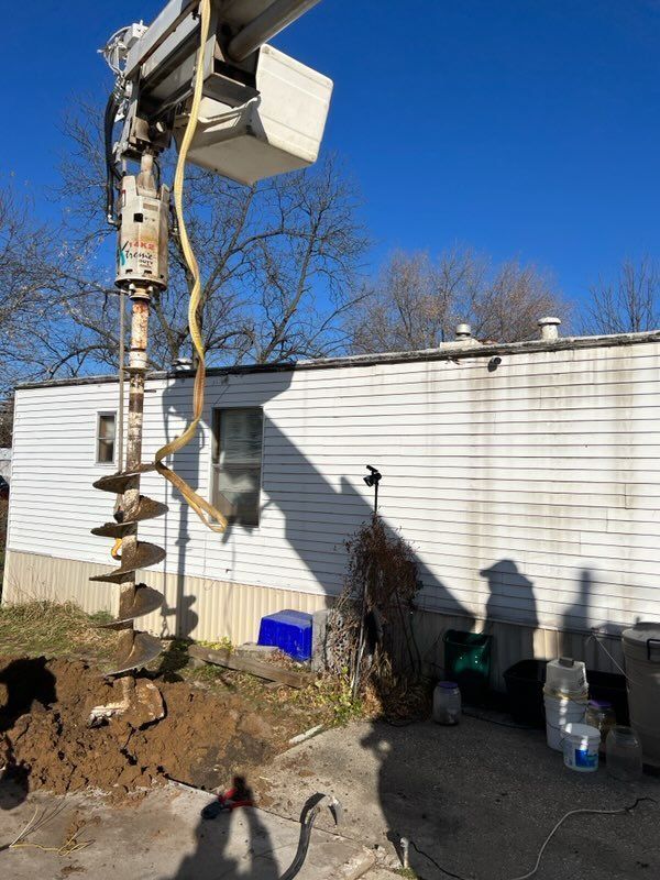 Utility pole with transformer and ladder beside a white building on a sunny day