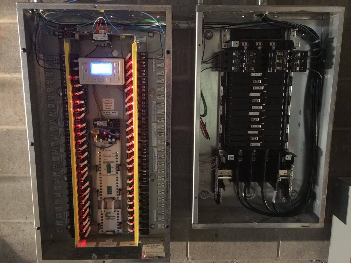 Open electrical control panel with circuit boards, wiring, and a glowing display inside a metal cabinet.