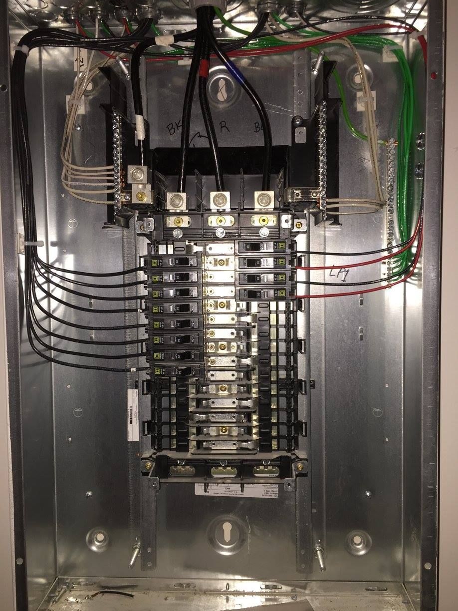Open electrical breaker panel with rows of circuit breakers and wiring inside a metal enclosure