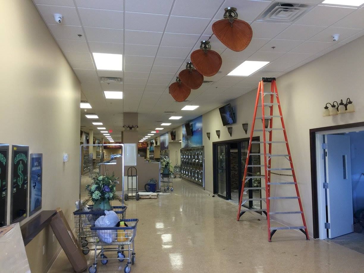 Hallway with hanging pumpkins, a red ladder, and display shelves in a bright indoor space