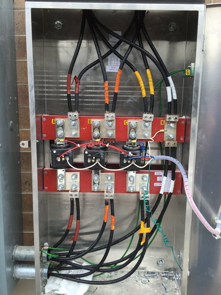 Open electrical control panel with wiring, relays, and colored cable connectors.