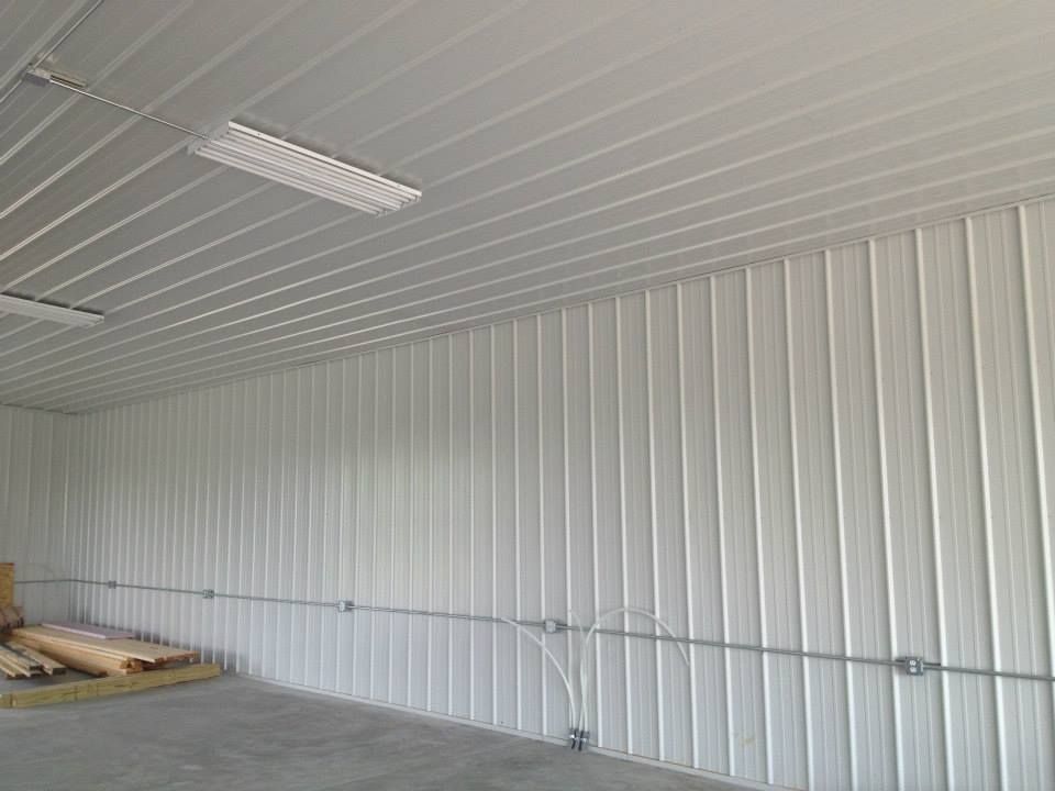 Empty white metal-walled room with corrugated ceiling and a fluorescent light fixture