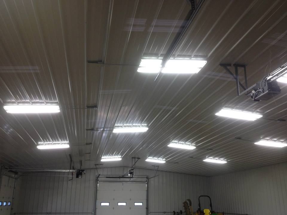 Interior of a large warehouse with bright fluorescent ceiling lights and a roll-up garage door.