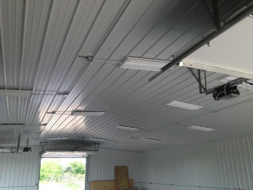 Interior of a metal building with a corrugated ceiling, skylights, and a partially open garage door