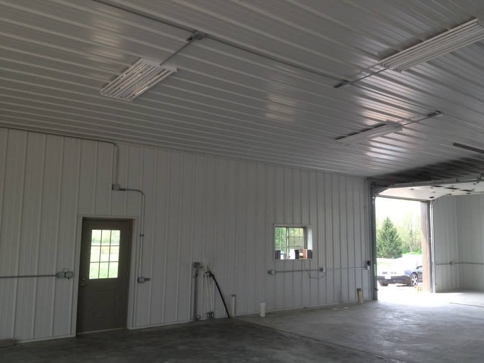 Empty white metal garage interior with a door, small window, and open bay to daylight