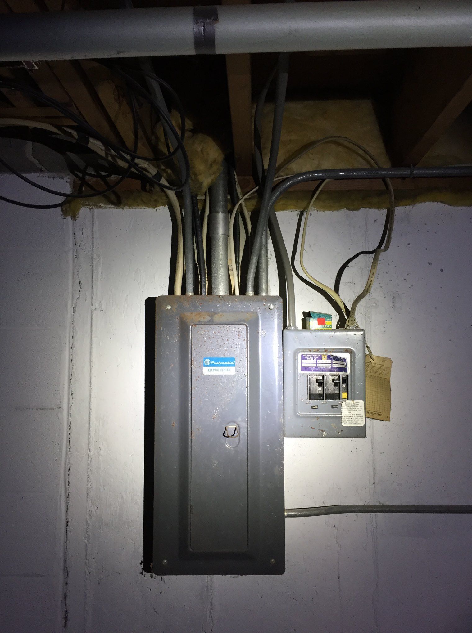 Electrical panel and meter box with exposed wiring on a wall in a utility area.