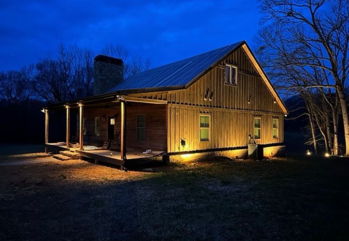 Wooden cabin lit warmly at night under a deep blue sky