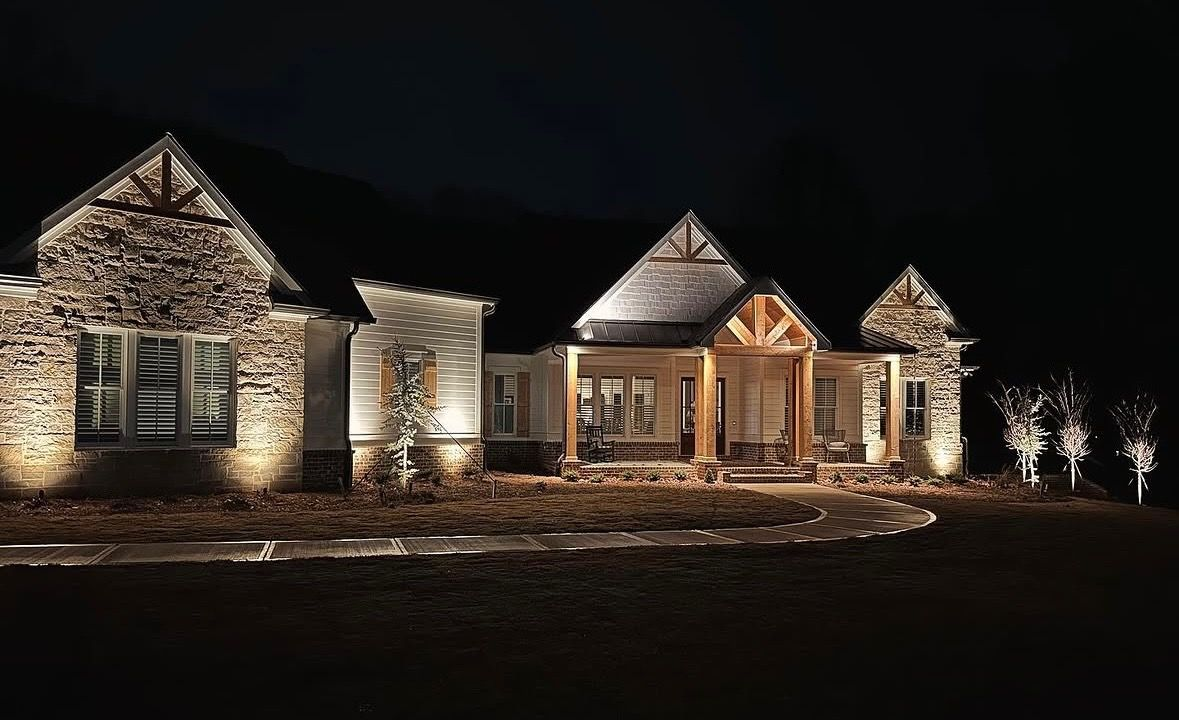 Lit stone house exterior at night with warm lights and dark sky