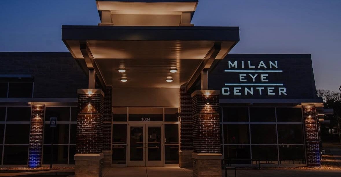 Entrance of a commercial building at dusk, with lit stone columns and sign
