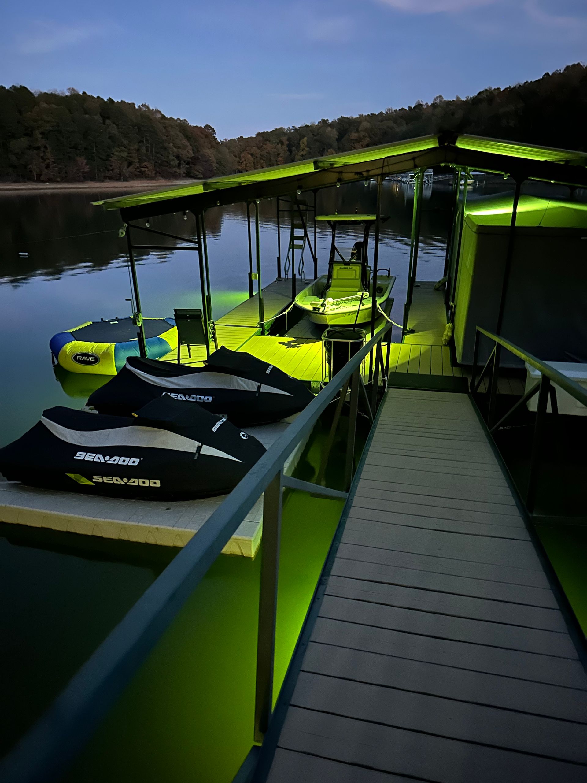 Neon yellow jet skis docked beside a lake on a floating pier at dusk