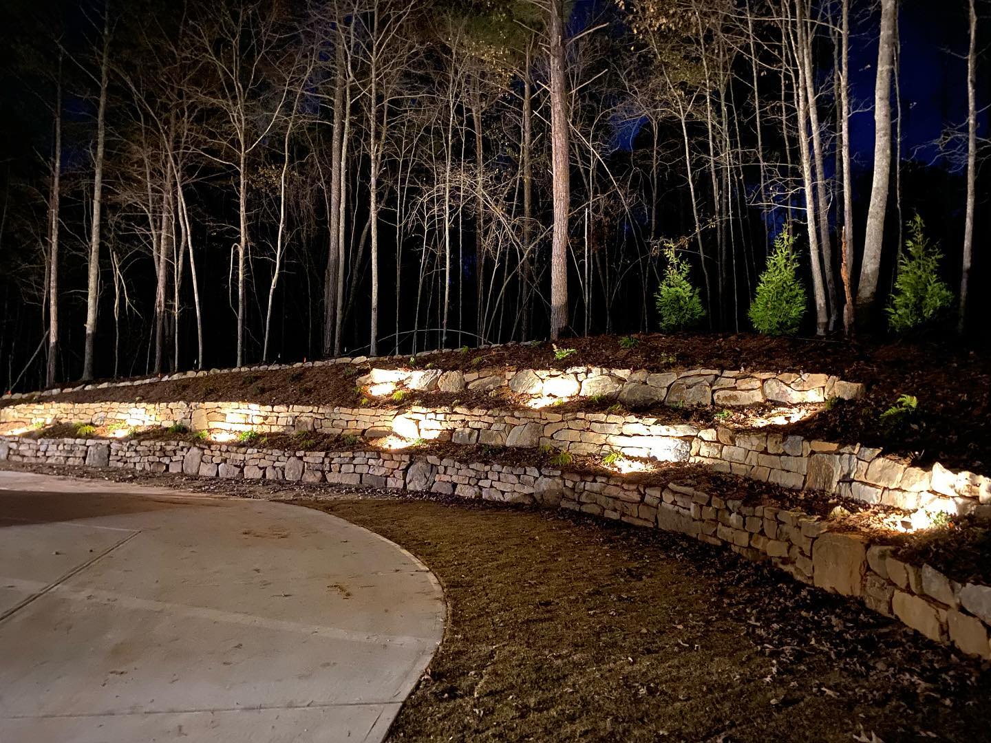 Multi-tier stone retaining wall with landscape lighting