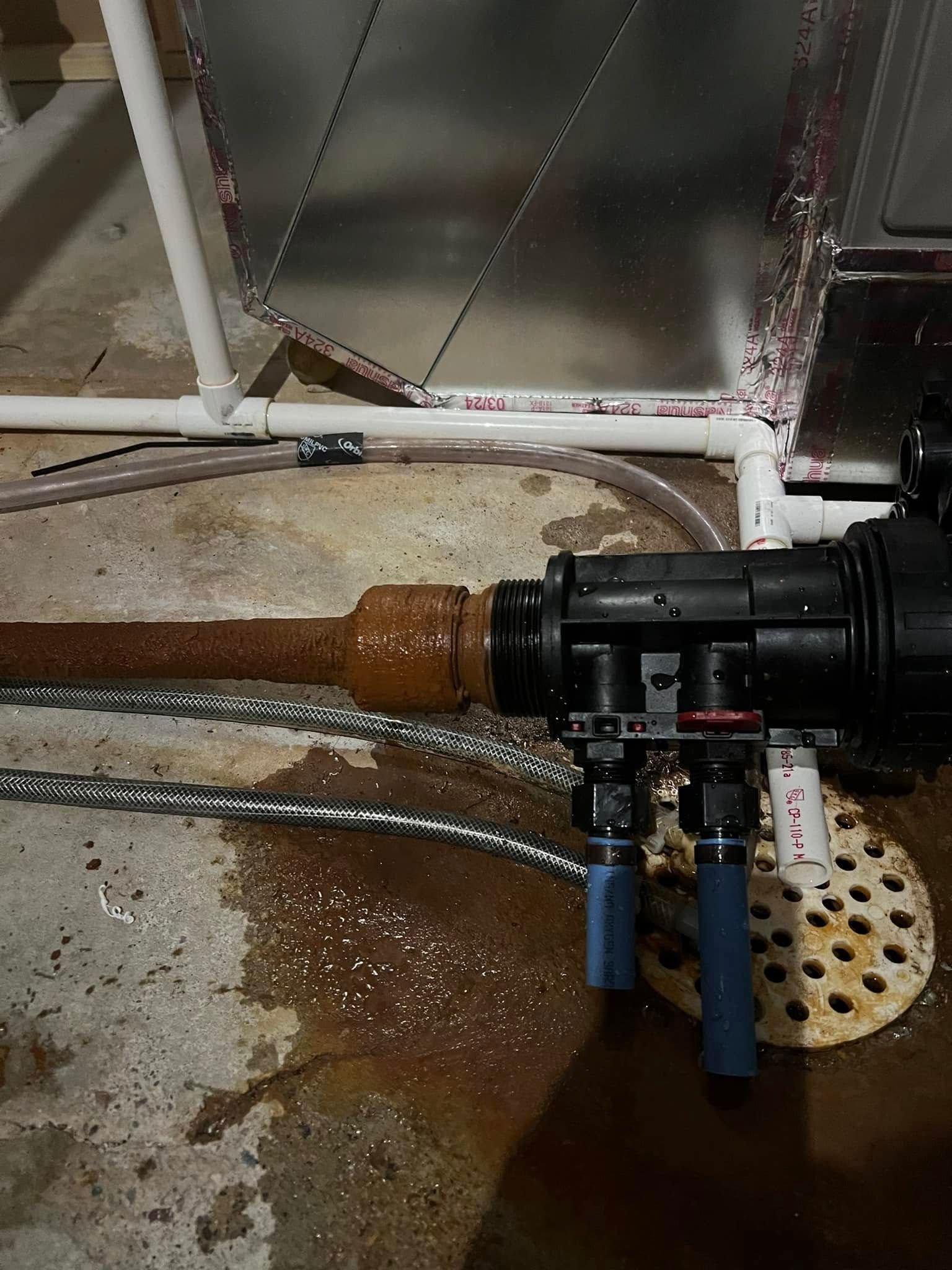 A rusty pipe is connected to a valve in a basement.