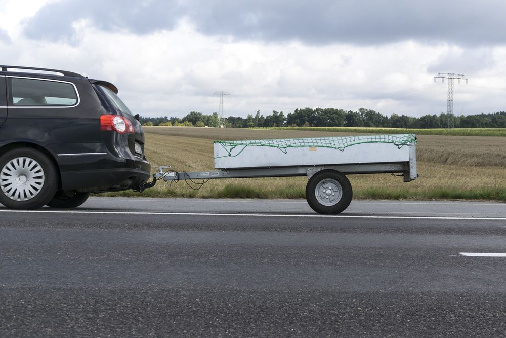 Black Car Towing a White Trailer on a Road — Towform Trailers in Brocklehurst, NSW