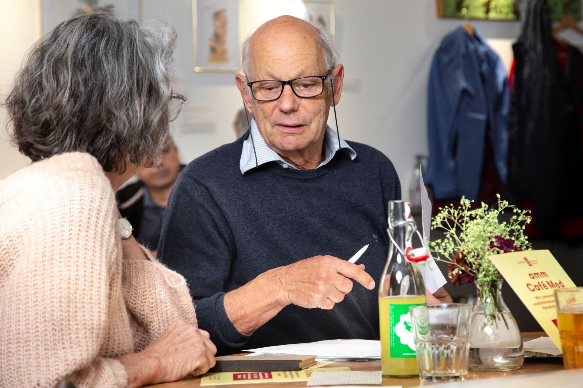 Ein Mann und eine Frau sitzen an einen Tisch und sprechen miteinander.