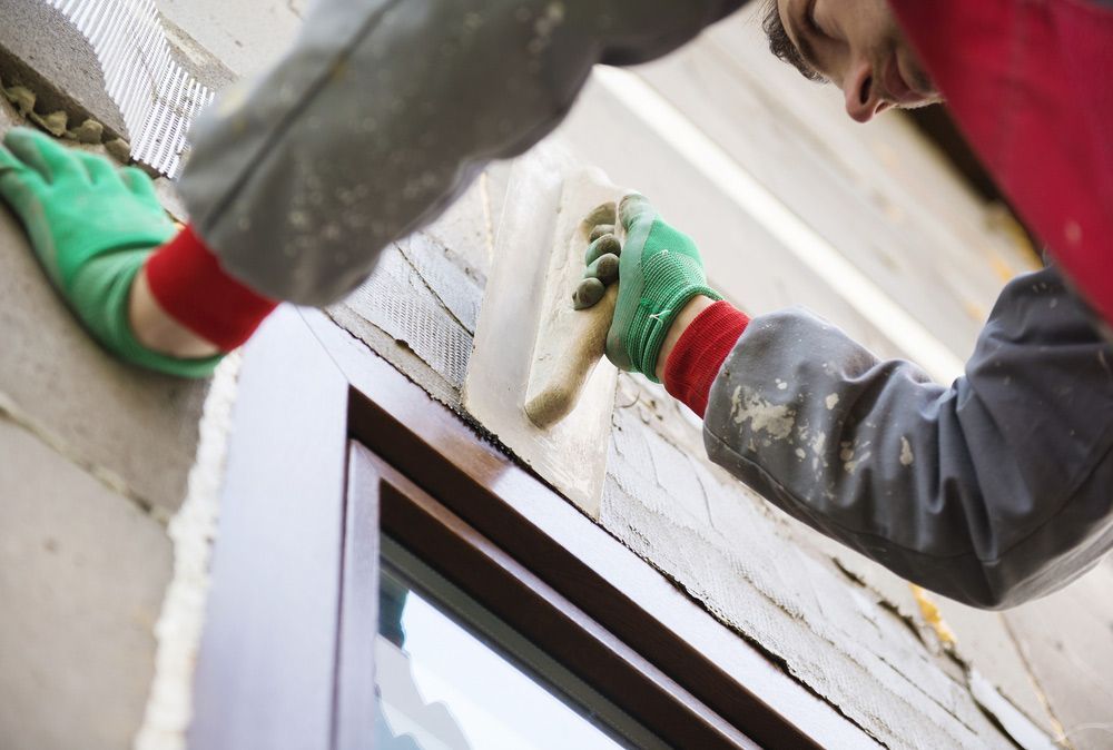 A Man is Plastering a Window Frame With a Trowel — A. Webber Building in Nowra, NSW