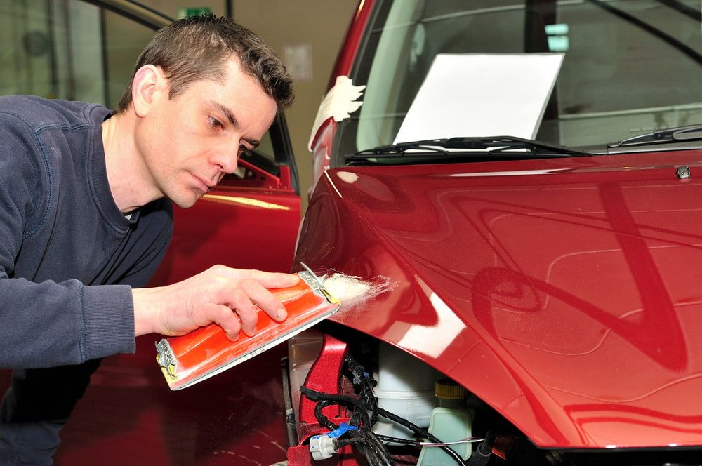 A Man is Working on the Hood of a Red Car — Bowen Mechanical & Haulage in Bowen, QLD