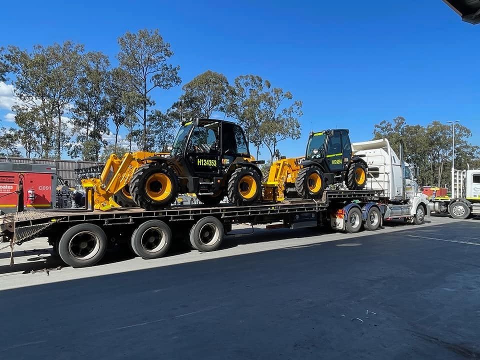 A Truck is Carrying a Load of Tractors on a Trailer — Bowen Mechanical & Haulage in Bowen, QLD