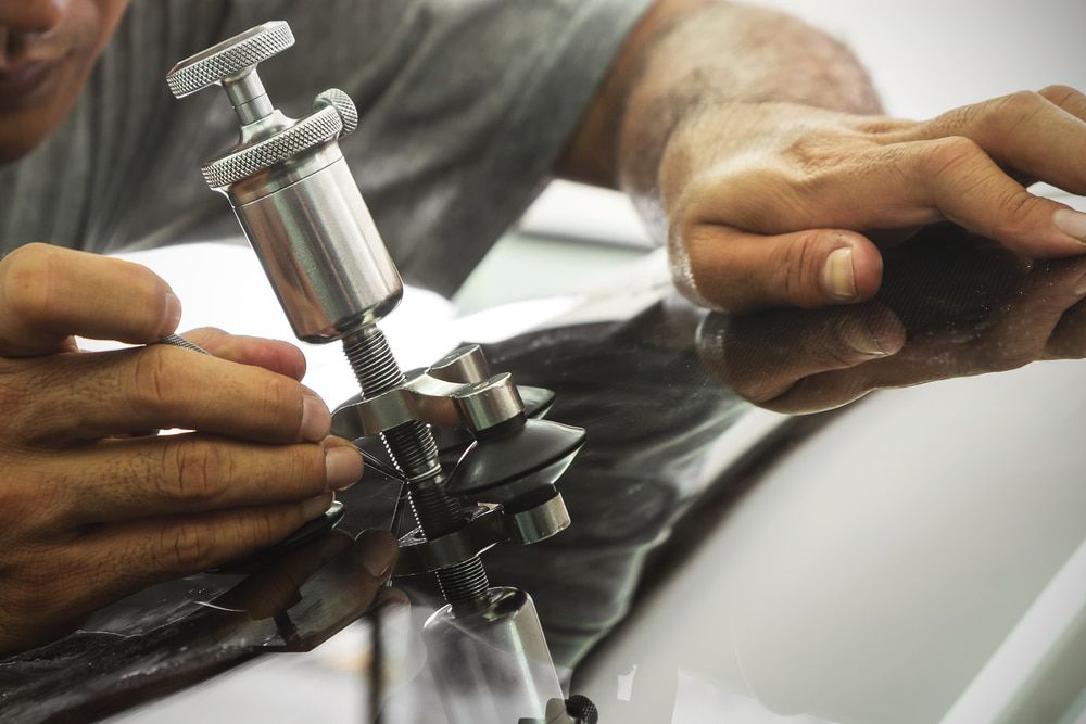 A Man is Working on a Car Windshield With a Tool — Bowen Mechanical & Haulage in Bowen, QLD