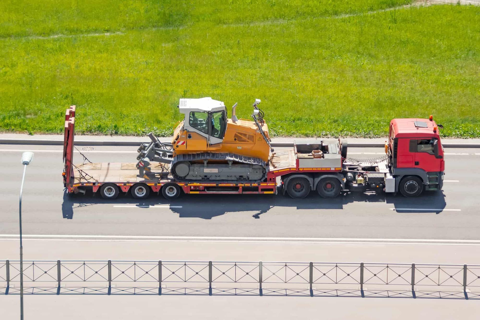 A Red Truck is Carrying a Bulldozer on a Flatbed Trailer — Bowen Mechanical & Haulage in Bowen, QLD